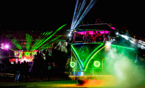 night time burning man scene with a neon VW bus , lasers, and dancers